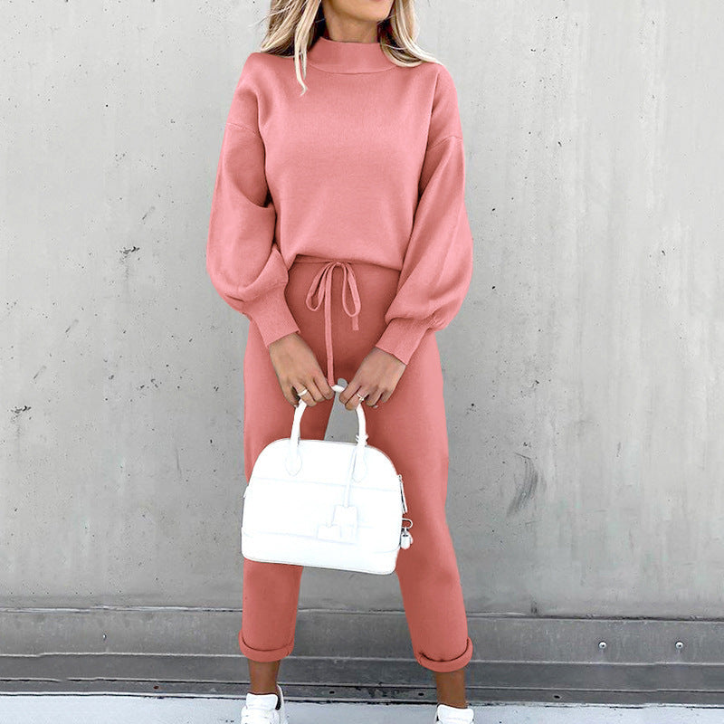 A woman wears a dusty pink fleece sweater suit with long cuffed sleeves, mock neck, and drawstring waist trousers.