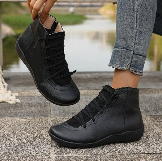 Black flat ankle boots with side zippers and front lacing, featuring a soft, rounded-toe leather-look design.