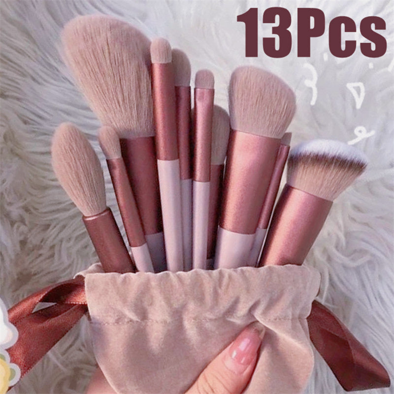 13-piece makeup brush set in a pink velvet pouch with metallic rose gold handles and soft, light pink bristles.