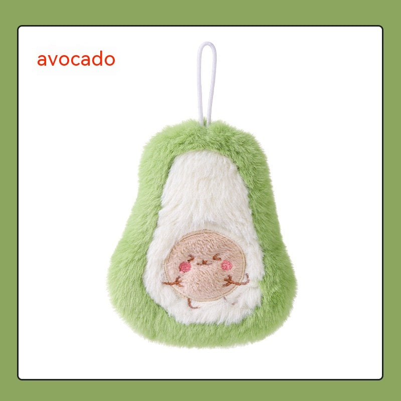 Soft, plush avocado-shaped hand warmer with a smiling face on the pit and a white hanging loop. Green and cream fur.