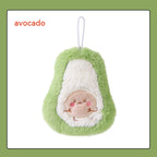Soft, plush avocado-shaped hand warmer with a smiling face on the pit and a white hanging loop. Green and cream fur.