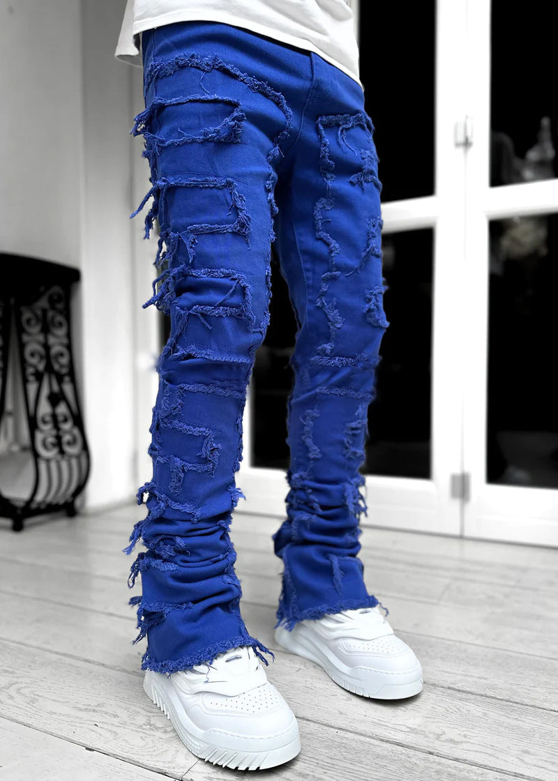 Bright blue stacked denim jeans with heavy distressed fringe detailing and a tight, ripped patch fit.
