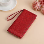 A shiny red glitter clutch for women with a wrist strap and gold zipper closure, set against a light background.