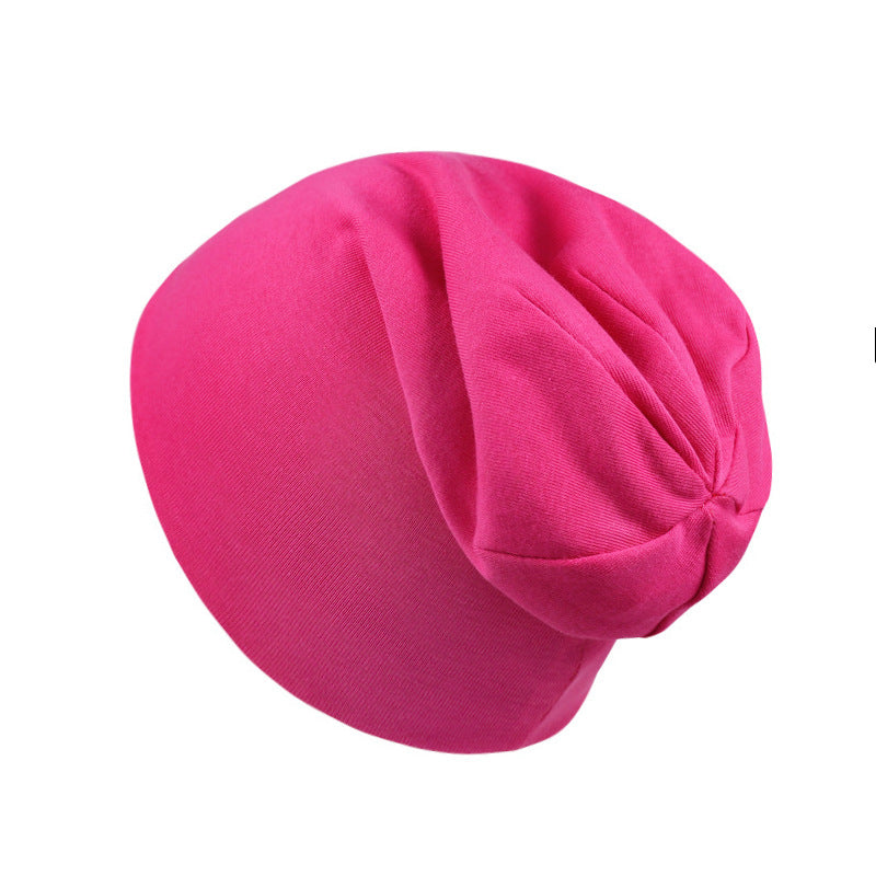 A plain, hot pink newborn beanie cap made of soft cotton fabric with a slouchy, comfortable fit.