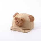 Beige corduroy baby hat with fuzzy bear ears and a cute plush bear face appliqué, featuring a soft, brimmed design.