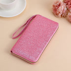 A sparkling pink glitter clutch with a wrist strap and gold zipper closure.