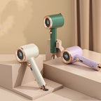 Three portable handheld garment steamers in green, white, and lilac with rose gold accents on tiered display pedestals.