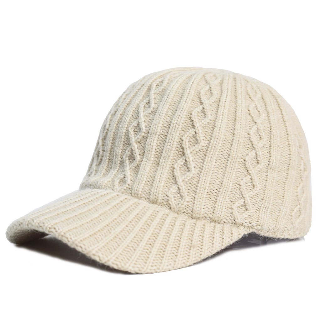 Beige knitted baseball cap with cable-knit texture and ribbed brim, isolated on a white background.