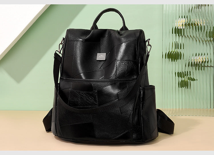 Black, minimalist, western-style leather patchwork backpack with a top handle, side pockets, and silver logo detail.