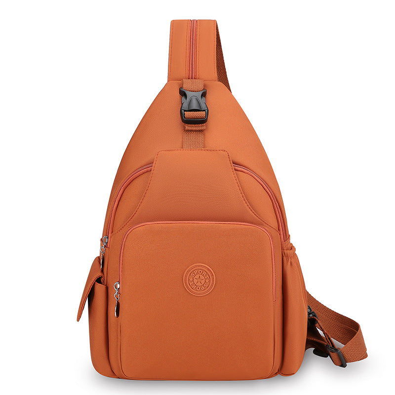 Orange waterproof crossbody chest bag with zipper pockets, buckle strap, and a circular "SPORT" logo patch on the front.