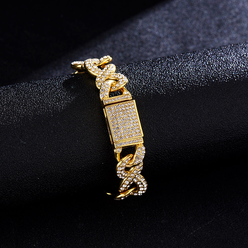 Gold-tone Cuban link bracelet encrusted with white crystals, featuring a rectangular paved clasp on a black surface.