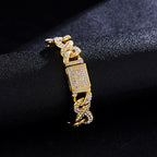 Gold-tone Cuban link bracelet encrusted with white crystals, featuring a rectangular paved clasp on a black surface.