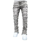 Grey distressed stacked jeans for men featuring heavy ripped detailing, frayed patches, and a tight, slim fit.