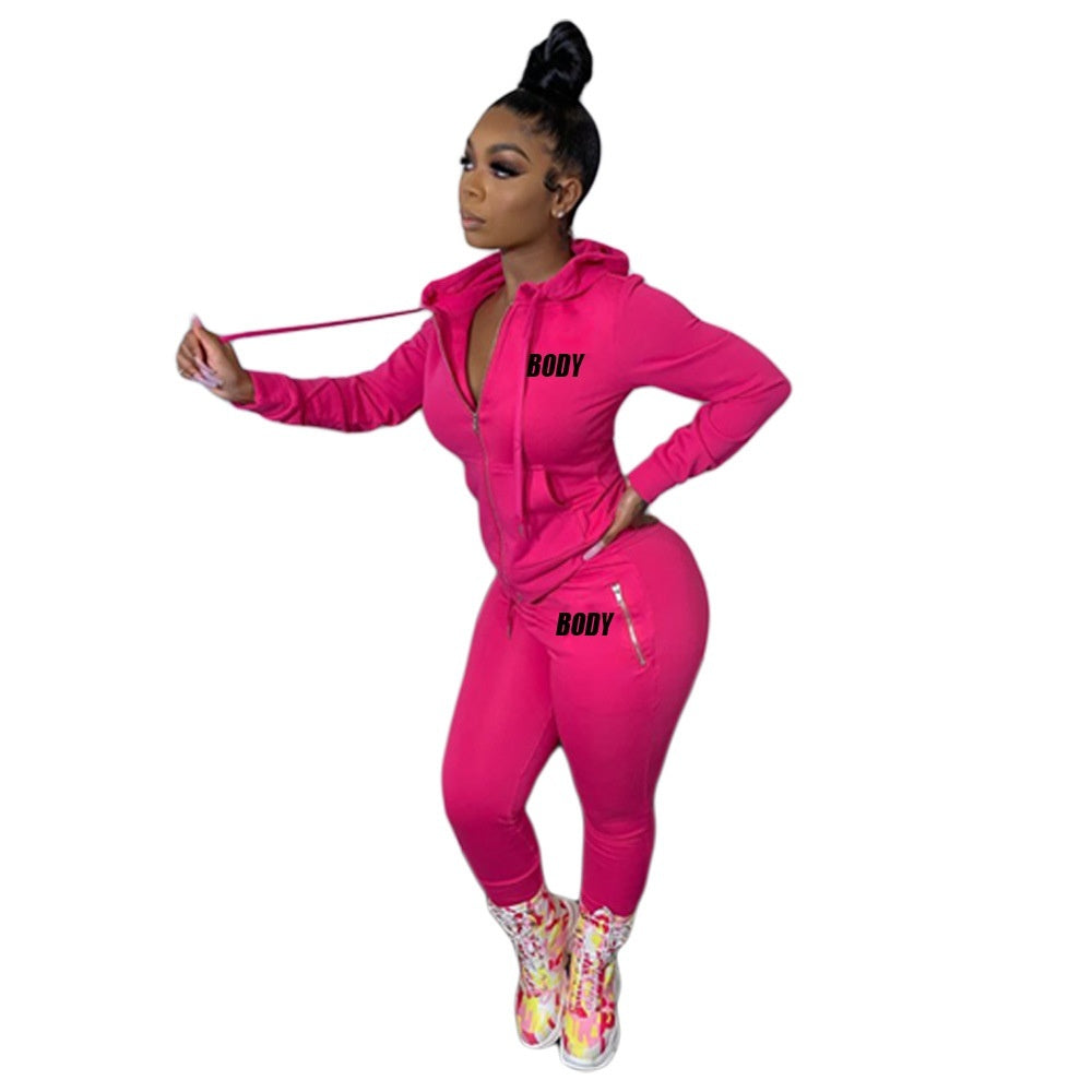Model wearing a hot pink hooded zipper tracksuit with "BODY" text, featuring long sleeves and fitted joggers.
