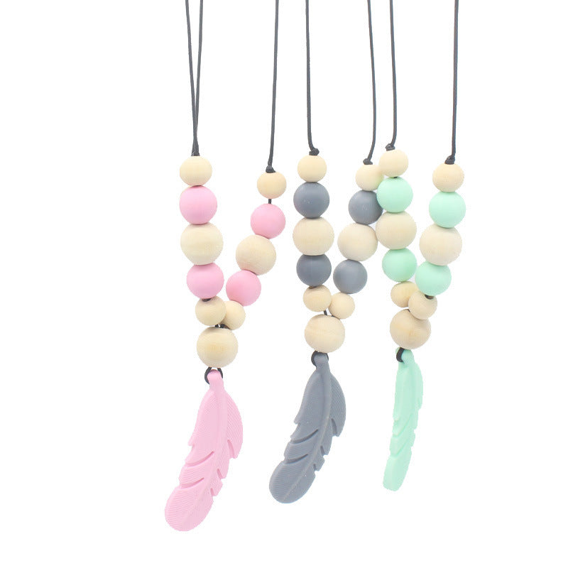Three silicone feather teether necklaces with wooden and pastel silicone beads on black cords against a white background.