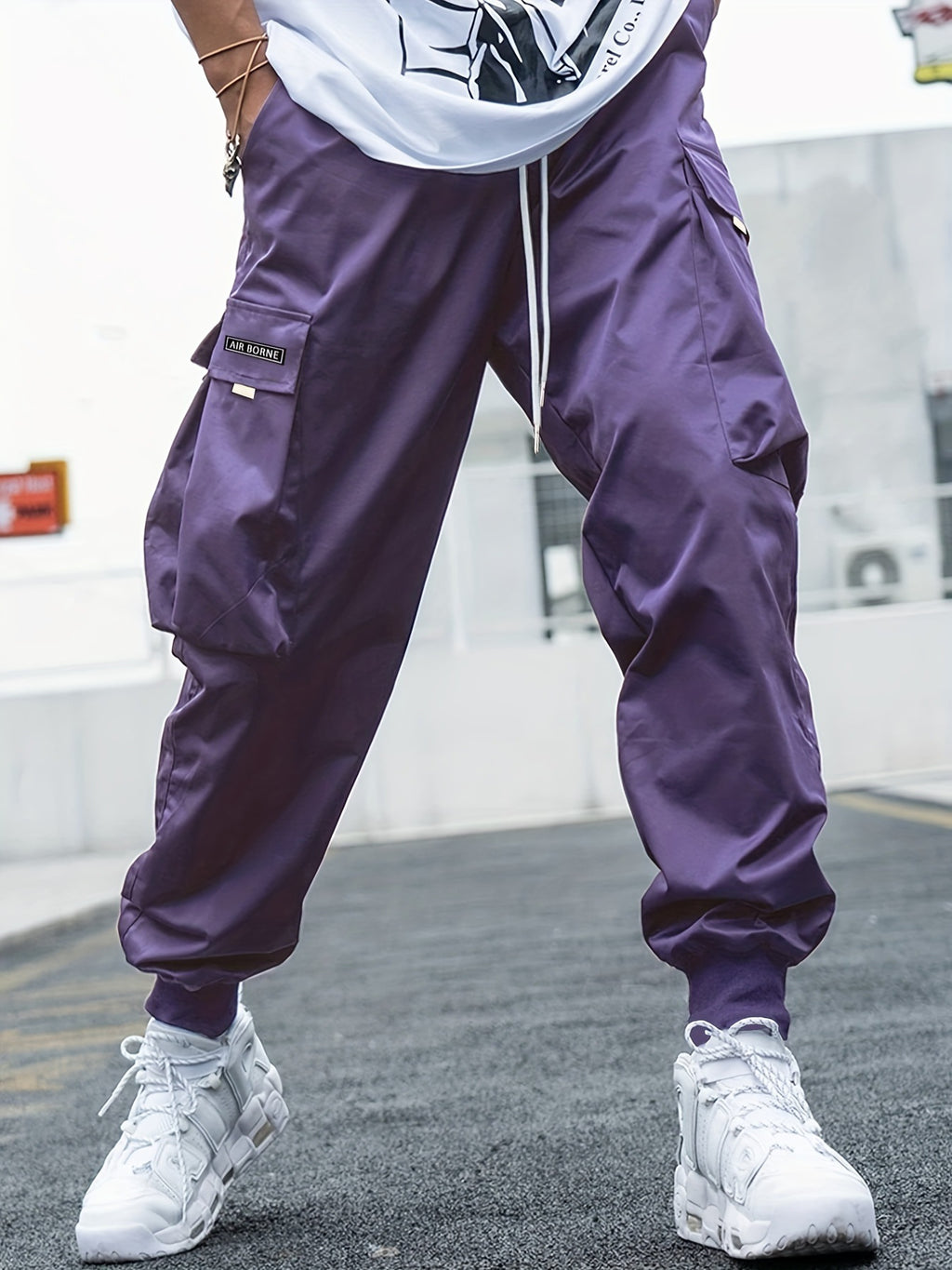Purple cargo pants with side pockets, drawstring waist, and elastic cuffs in a baggy, hip-hop streetwear style.