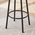 Matte black metal bar stool legs with a circular footrest ring, standing on a light-colored textured rug.