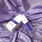 V34 purple teeth whitening mousse pump and box on a shimmering, light-reflecting purple fabric background.