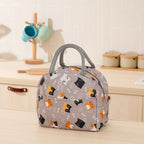 Gray insulated lunch bag with cat and fish bone pattern, gray handles, and front pocket on a kitchen counter.