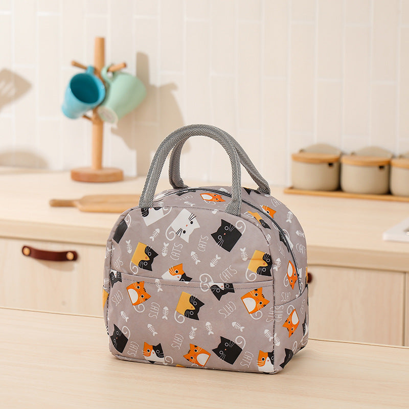 Gray insulated lunch bag with cat and fish bone pattern, gray handles, and front pocket on a kitchen counter.