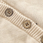 Close-up of beige knitted baby clothes featuring ribbed trim and round wooden-style buttons.