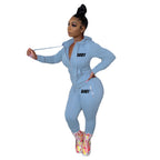 A woman models a light blue, zip-up hooded sweatshirt and matching joggers set with "BODY" text printed on both.