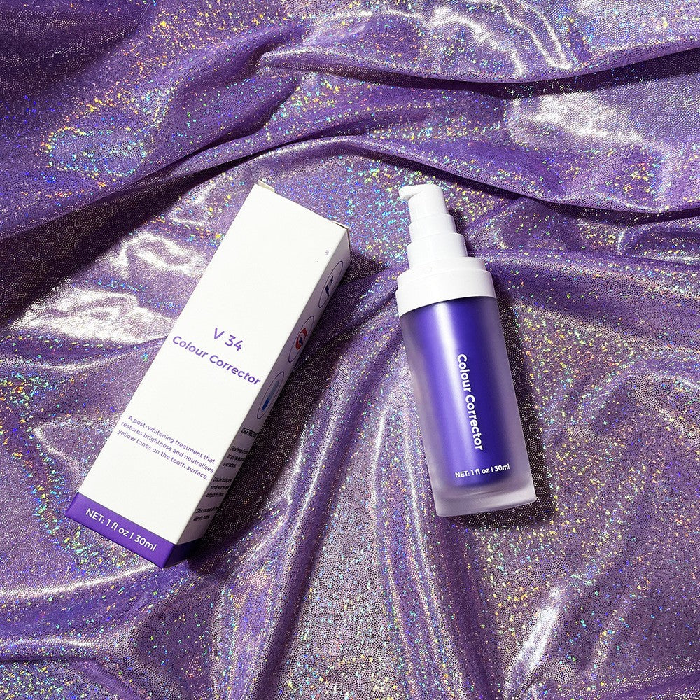 V34 purple teeth whitening mousse bottle and box on shiny, iridescent purple fabric.