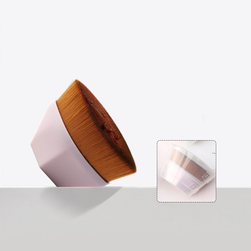 Flat-top makeup brush with dense brown bristles, a pastel pink handle, and a protective clear plastic cap.