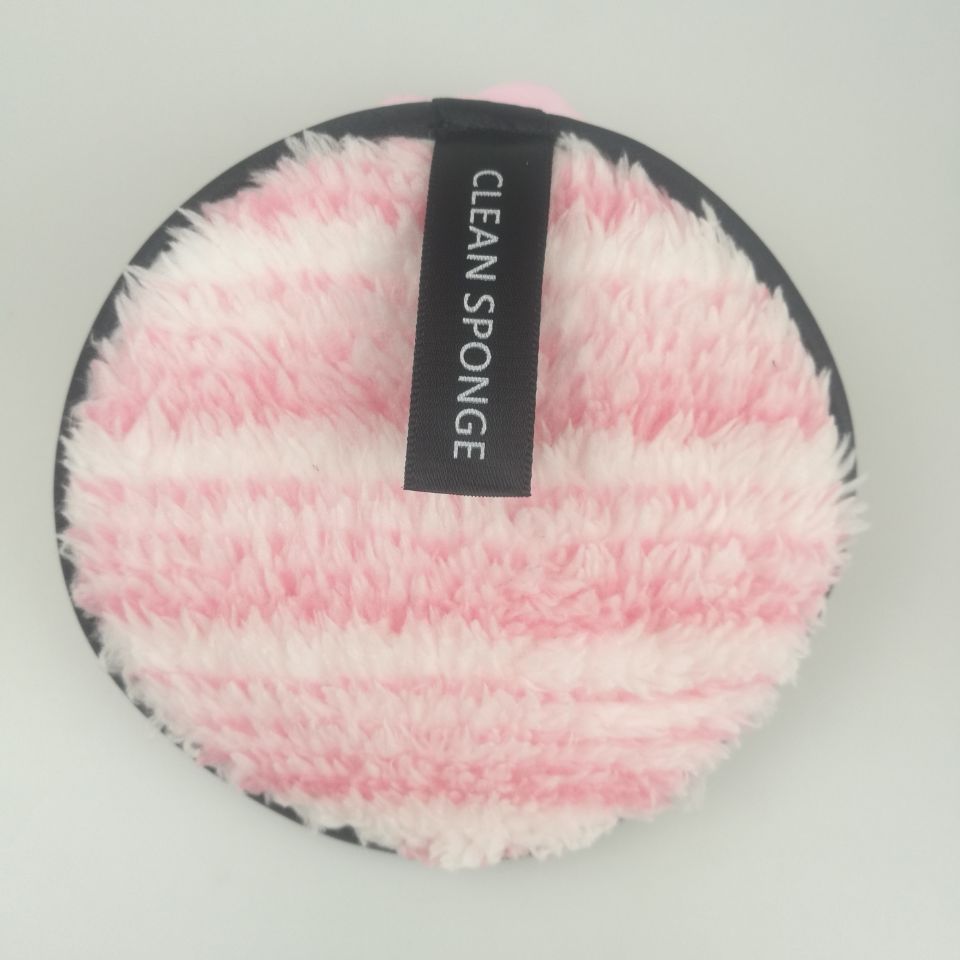 Round, pink and white striped fuzzy cleansing sponge with a black "CLEAN SPONGE" label on a light gray background.