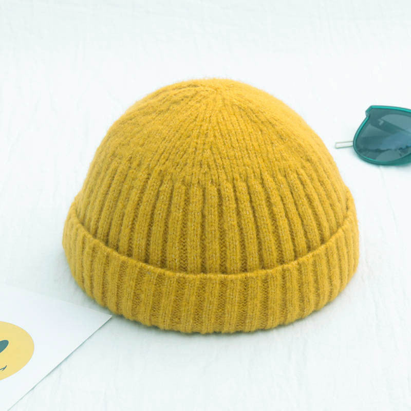 Mustard yellow ribbed knit beanie with a cuffed, brimless, hip-hop retro design on a white background.