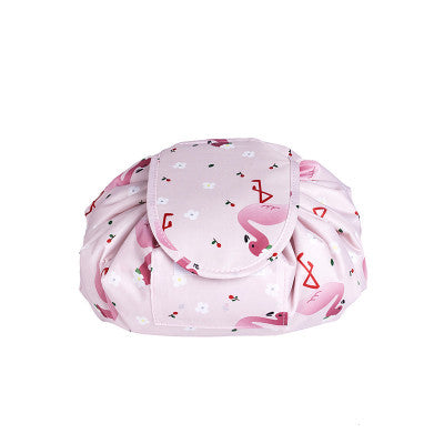 Pink drawstring cosmetic bag featuring a flamingo and white flower pattern. Compact, soft fabric, fold-over closure.