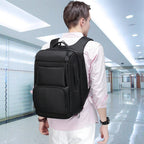 A man wears a sleek, black, minimalist multifunctional backpack with multiple compartments in a bright, modern hallway.