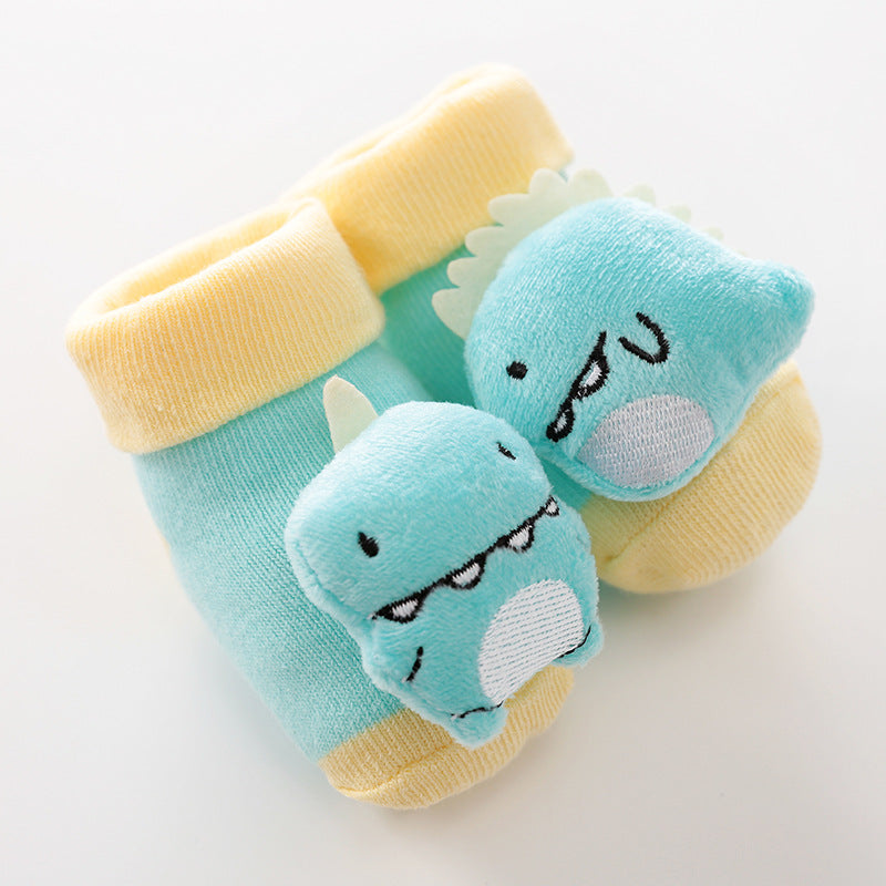 Turquoise baby socks with yellow cuffs and a 3D plush blue dinosaur character on the toe. Soft knit material.