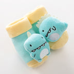 Turquoise baby socks with yellow cuffs and a 3D plush blue dinosaur character on the toe. Soft knit material.