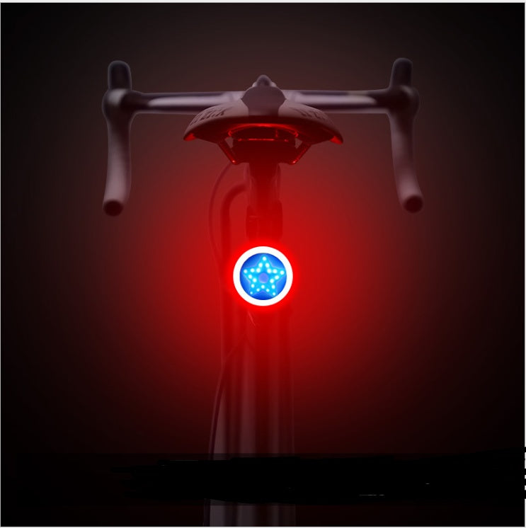 Round USB bicycle taillight mounted on a seat post, featuring a bright blue star-shaped LED light with a red halo.