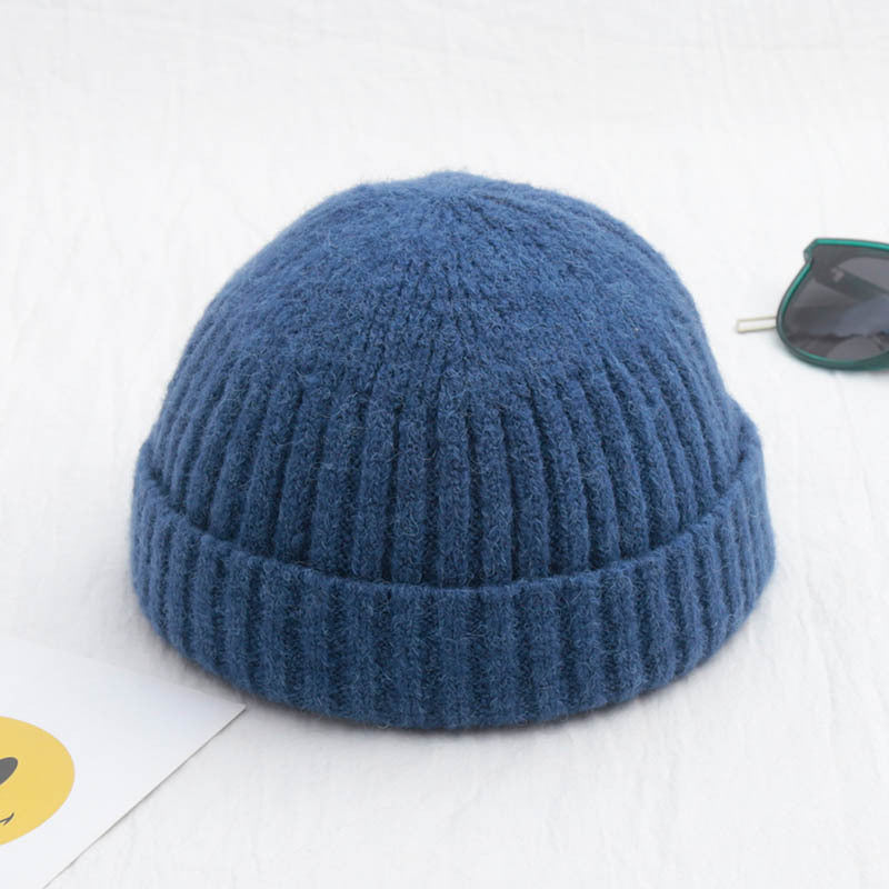 A blue, rib-knit fisherman beanie made of soft, textured material, presented on a white surface.
