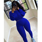 Woman wearing a royal blue, long-sleeve cropped top and matching high-waisted ribbed leggings sports set.
