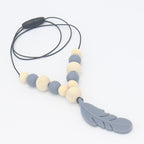 Baby teether necklace with grey feather charm, alternating wood and grey silicone beads on a black cord.