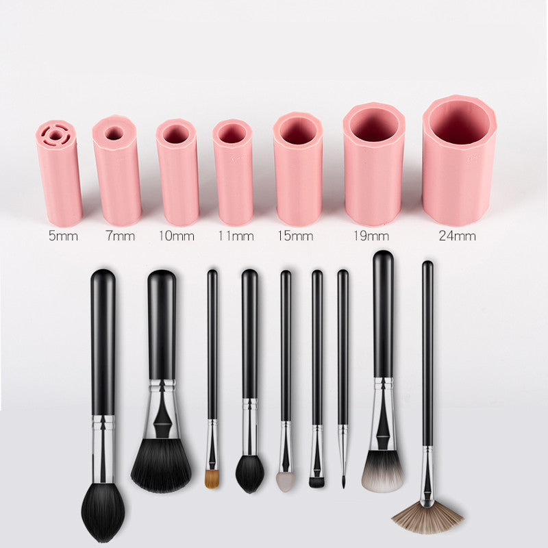 Seven pink silicone brush cleaner sleeves of varying sizes and matching black makeup brushes on a white background.