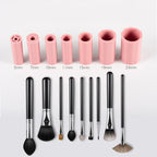 Seven pink silicone brush cleaner sleeves of varying sizes and matching black makeup brushes on a white background.