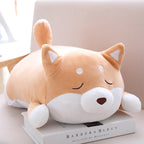 Cute, soft, tan and white Shiba Inu plush pillow lying on a book, featuring closed eyes and a small brown nose.