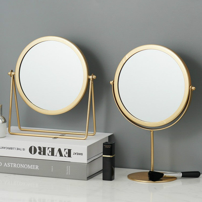 Two round, gold-framed vanity mirrors on a marble surface against a grey background.