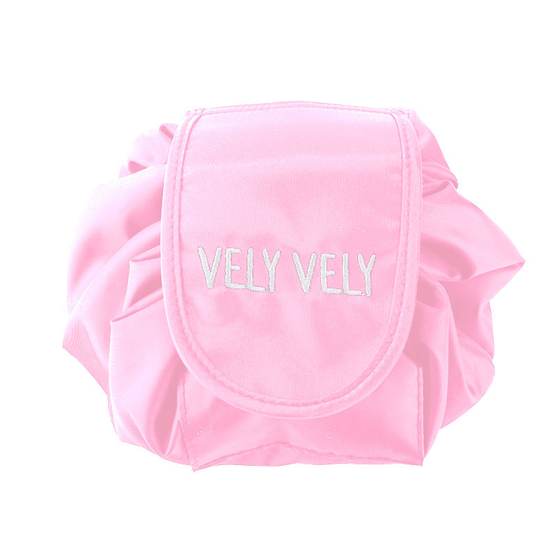 Pink drawstring cosmetic bag by VELY VELY, featuring a circular, fold-out design with white embroidered branding.