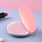 Pink round portable LED makeup mirror with a charging port, set on a blue and pink background.