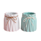 Two fluted ceramic makeup brush holders in white and mint green, each tied with a decorative twine bow.