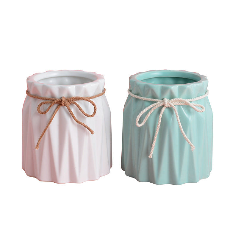 Two fluted ceramic makeup brush holders in white and mint green, each tied with a decorative twine bow.
