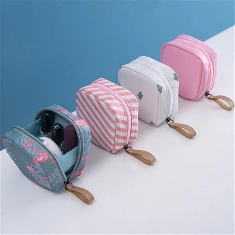 Four small fabric makeup bags with zippers, featuring floral, striped, cactus, and solid pink designs.
