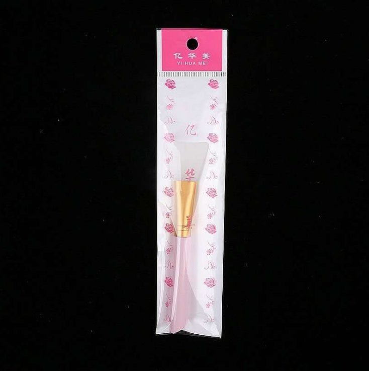 Silicone face mask brush in branded plastic packaging with a pink handle, gold ferrule, and white silicone head.