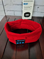 Red knitted Bluetooth sports headband with a control panel and matching packaging box on a dark wooden surface.