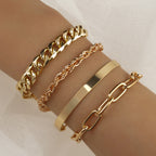 Four gold-tone bracelets on a wrist, featuring a thick Cuban chain, a rope chain, a smooth cuff, and a paperclip link.